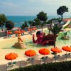 Piscina con decorazioni a tema pirata, ombrelloni arancioni e vista sul mare.