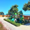 Parco giochi per bambini con scivoli verdi e torri a forma di castello.