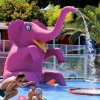 Statua di elefante rosa spruzza acqua in una piscina.