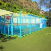 Un campo da gioco per bambini recintato con struttura colorata, su prato verde.