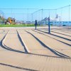 Campo da beach volley su sabbia con rete, circondato dal mare e lettini.
