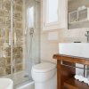 Un bagno moderno con doccia, lavabo su mobile in legno e asciugamani arrotolati sugli scaffali.