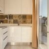 Cucina moderna con mobili bianchi, piastrelle decorative e porta-finestra aperta verso il giardino.