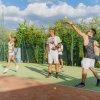 Persone che giocano a tennis su un campo all'aperto sotto un cielo nuvoloso.