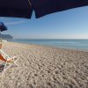 Spiaggia con ombrelloni blu e sdraio arancioni, vista sul mare calmo sotto un cielo sereno.