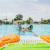 Due persone che nuotano in piscina, con palette colorate in primo piano.
