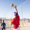Un uomo gioca a beach volley sulla spiaggia, alza la palla per un attacco.