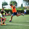 Ragazzi giocano a calcio su un campo in erba sintetica con maglie sportive colorate.