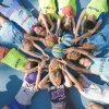 Bambini distesi a terra a cerchio con palloni da basket al centro.