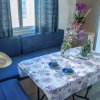 Tavolo apparecchiato con tovaglia floreale, fiori in vaso e seduta blu.