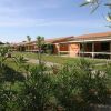 Bungalow allineati in un villaggio vacanze, con giardini curati e piante fiorite.