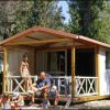 Una famiglia seduta davanti a una casetta con veranda in un ambiente alberato.