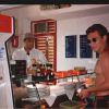 Due uomini in una gelateria, uno in costume da bagno. Frigorifero con latte sulla sinistra.