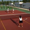 Tre persone giocano a tennis su un campo all'aperto.