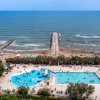Piscine vicino alla spiaggia con ombrelloni e persone.