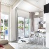 Interno di una casa con divano, tavolo da pranzo, cucina moderna e porte-finestre.