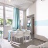 Sala da pranzo luminosa con tavolo bianco e sedie, tende blu e bianche, e vista sul giardino.