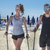 Due persone camminano sulla spiaggia con bastoni da trekking.