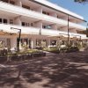 Edificio bianco a tre piani con terrazza e ampi ombrelloni.